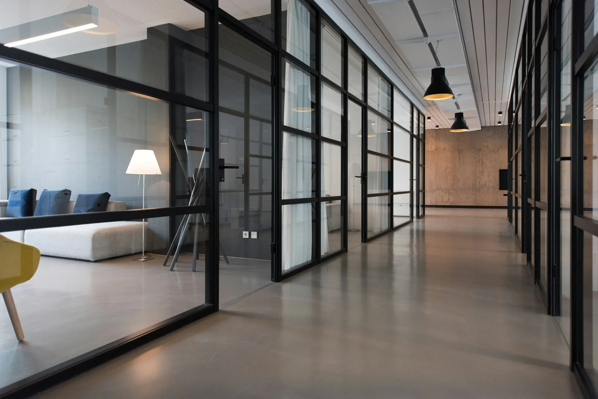 A light-filled modern business workspace with glass meeting rooms and warm wood details